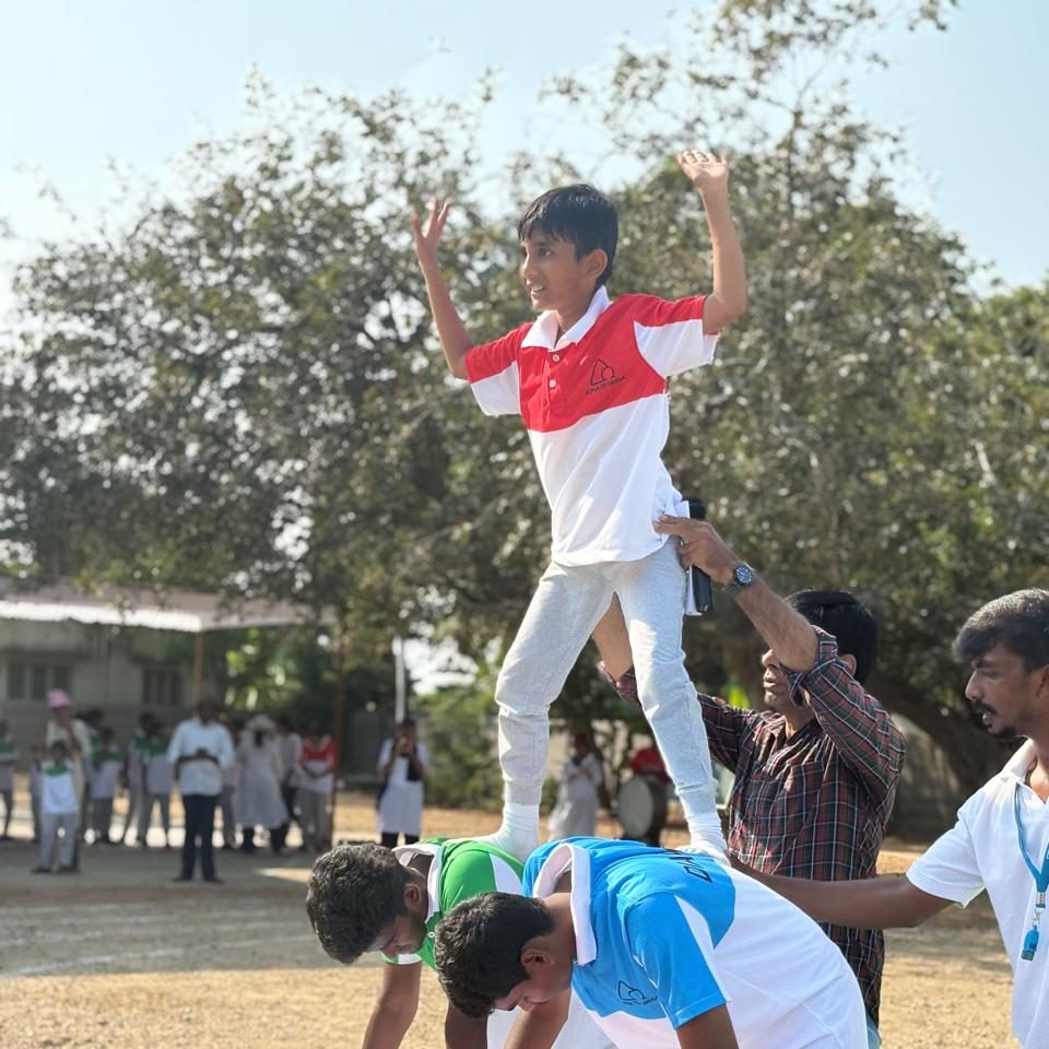 School children performing group balancing activity during outdoor sports event